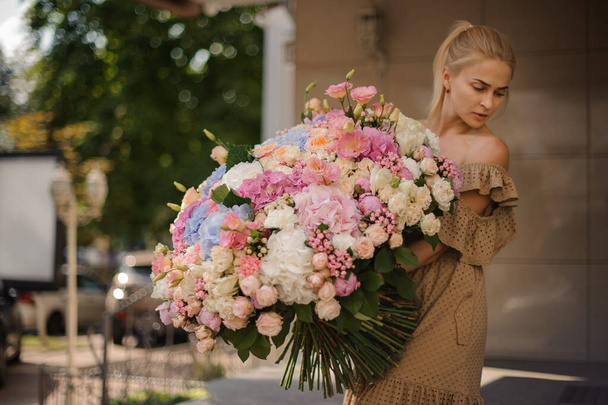 view of young blonde woman with huge bunch of different flowers in her hands - Φωτογραφία, εικόνα