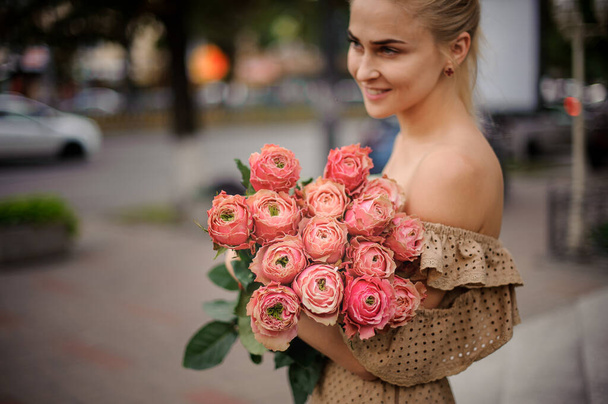 excellent view of rosebuds in flower bouquet in the hands of young smiling woman - Фото, изображение