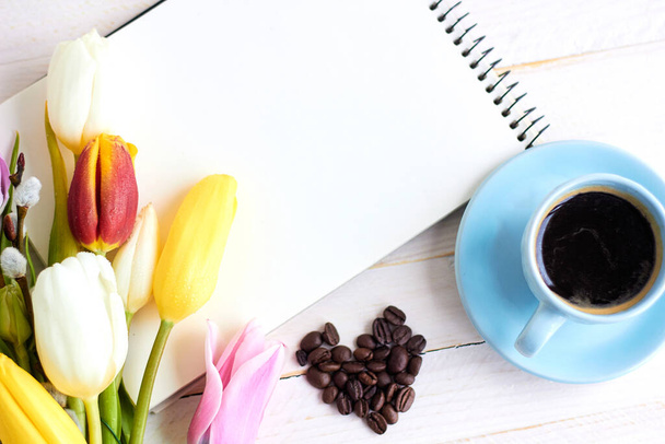 Frühlingsblumen mit Notizbuch auf hellem Holzgrund. Hintergrund für Grußworte, Einladungen und Postkarten. - Foto, Bild