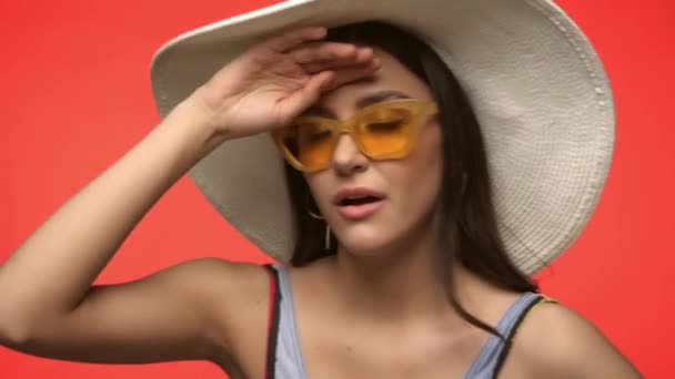 Femme en lunettes de soleil souffrant de chaleur isolée sur rouge - Séquence, vidéo