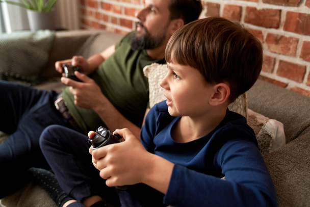 πατέρας και γιος παίζουν βιντεοπαιχνίδι στο σπίτι - Φωτογραφία, εικόνα