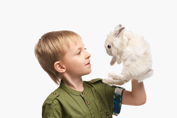 Little pretty boy holding fur rabbit baby. White cute pet. Happy easter - Фото, изображение