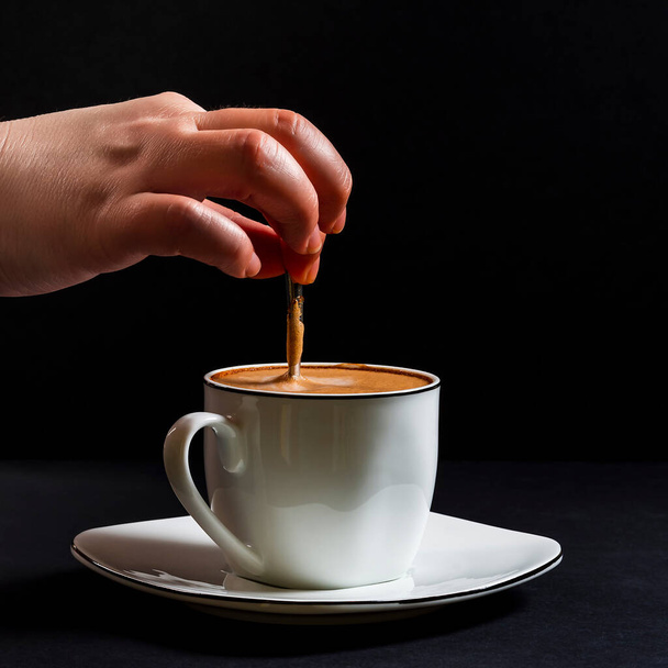 Woman's hand stirring a latte.This is a square-format photo taken on a black background under artificial light in a studio. - Fotó, kép