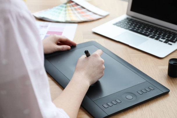 Professional designer with graphic tablet at wooden table, closeup - Foto, imagen