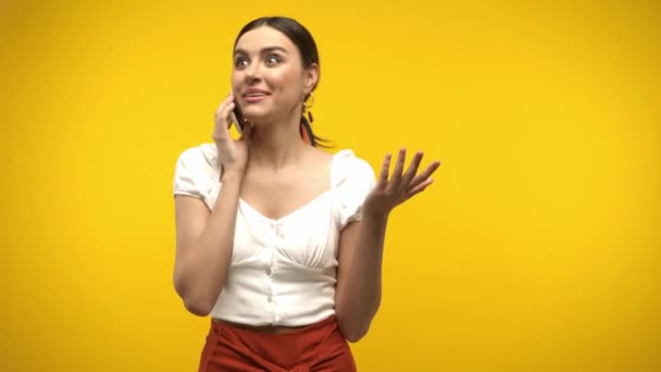 Vrolijke vrouw praten op mobiele telefoon geïsoleerd op geel - Video