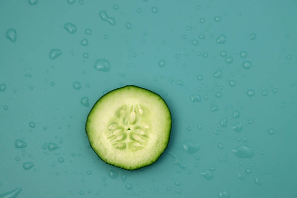 Ein kleiner Kreis frischer Gurken auf blauem Grund mit Wassertropfen. Kalorienarmes und wässriges Gemüse.  - Foto, Bild