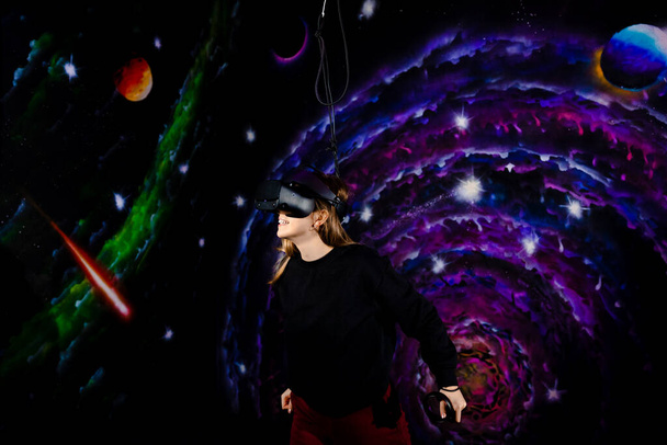 Smiling caucasian woman wearing vr glasses on the background of space, the girl smiling happily and enthusiastically while playing a virtual game. High quality photo - Zdjęcie, obraz