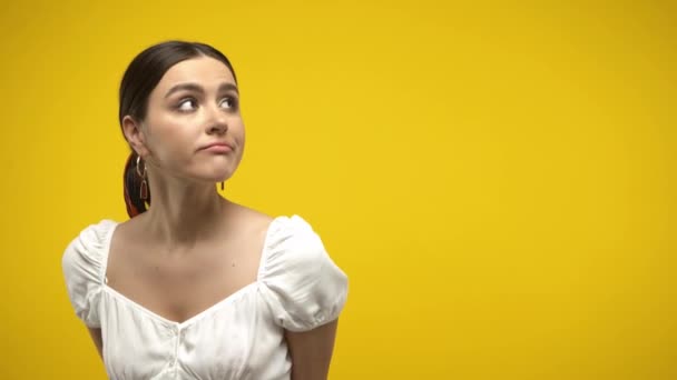 Pensive brunetka kobieta izolowane na żółty - Materiał filmowy, wideo