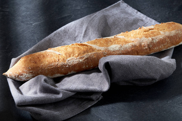 close up of baguette bread on kitchen towel - Foto, Imagem