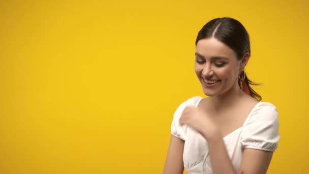 Θετική μελαχρινή γυναίκα κοιτάζοντας κάμερα απομονωμένη στο κίτρινο - Πλάνα, βίντεο