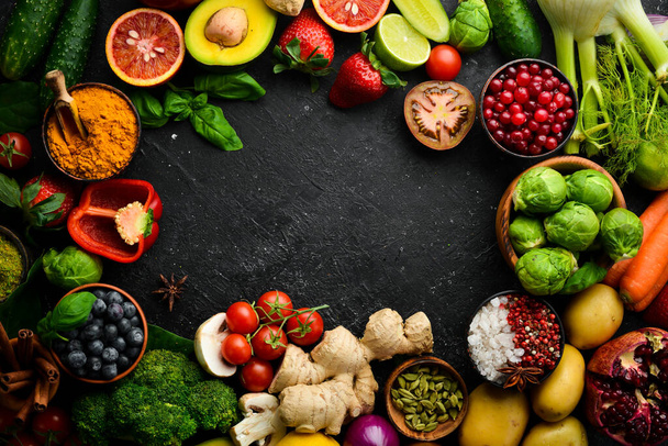 Fresh vegetables and fruits: fennel, avocado, pomegranate, berries, cabbage and basil. Organic healthy vegan food. On a black stone background. - Foto, imagen