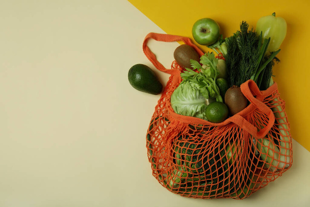 String bag with green vegetables on two tone background - Fotó, kép