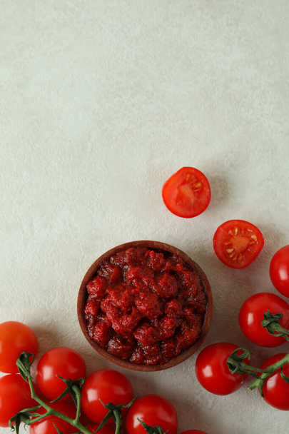 Wooden bowl with tomato paste and tomatoes on white textured table - 写真・画像