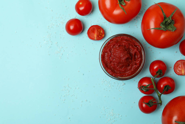 Bowl with tomato paste, tomatoes and salt on blue background - Φωτογραφία, εικόνα