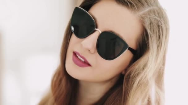 Beautiful businesswoman wearing stylish sunglasses and smiling, beauty face portrait of a caucasian european model as fashion, accessories and business people concept - Footage, Video