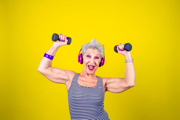 Feliz anciana entrenando levantando pesas sonriendo aislada - Foto, imagen