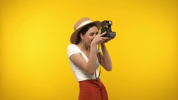 Donna in cappello da sole con fotocamera vintage isolato su giallo - Filmati, video