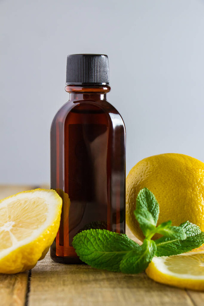 Aromatic oil with lemon and mint on a wooden background. Product for relaxation and spa therapy. - Foto, Imagem
