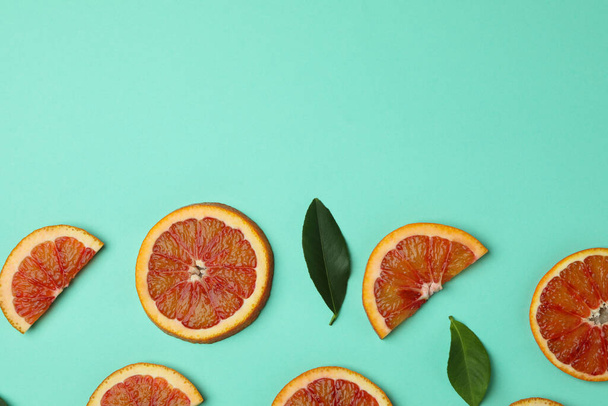 Red orange slices and leaves on mint background - Фото, зображення