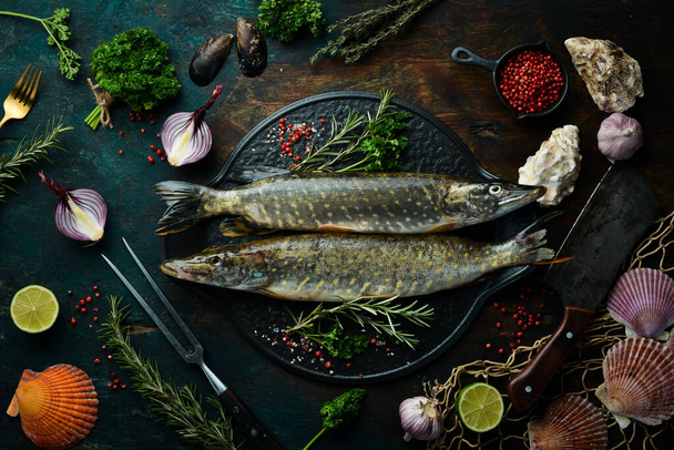 Two fish Pike with spices on a black stone plate. On a dark background. Top view. - Фото, зображення