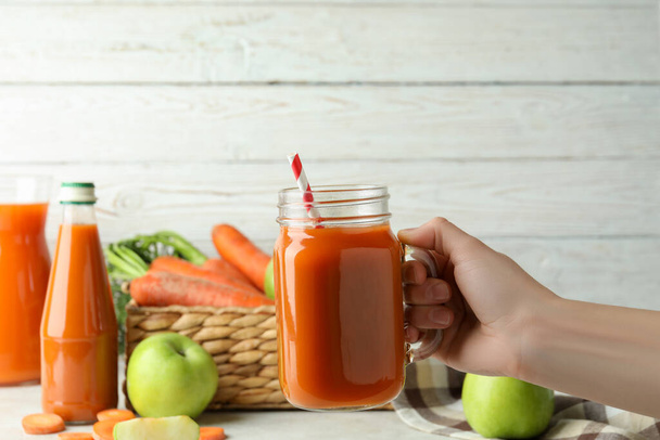 Female hand hold jar with apple - carrot juice - Photo, Image