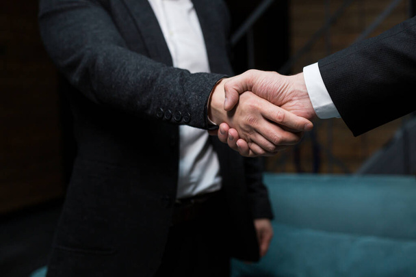Close up photo, two men in black business suits shaking hands - Zdjęcie, obraz