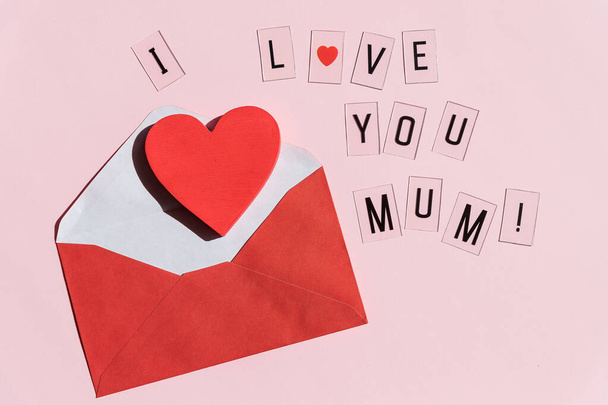 Phrase I LOVE MUM made of letters on pink background. Happy Mothers Day.greeting card .Creative Composition with red heart and envelope. Love and family concept.Copy space - Photo, image