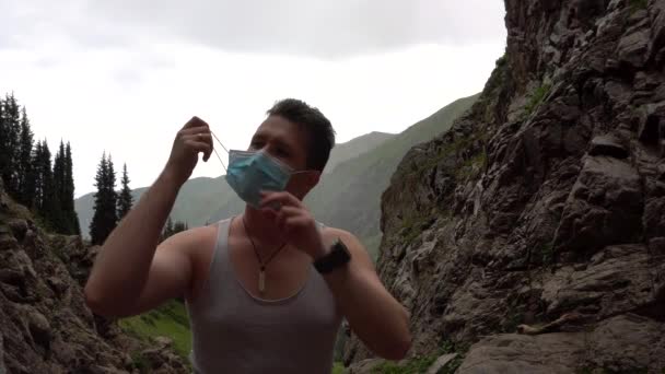 Парень в горах снимает свою медицинскую маску. - Кадры, видео
