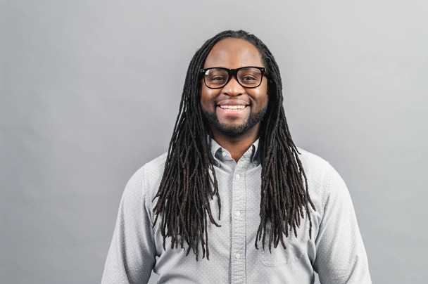 Smiling African-American man with dreadlocks isolated on grey - Фото, изображение