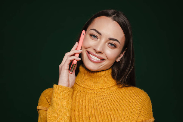 Happy beautiful girl smiling and talking on mobile phone isolated over green background - Фото, изображение