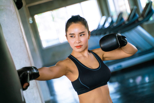 Boksör kadınlar boks stüdyosunda torba yumrukluyor. Asyalı kadın savunma egzersizi - Fotoğraf, Görsel