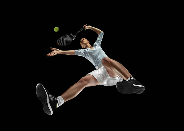 Female professional tennis player in action, motion isolated on black background, look from the bottom. Concept of sport, movement, energy and dynamic. - Foto, immagini