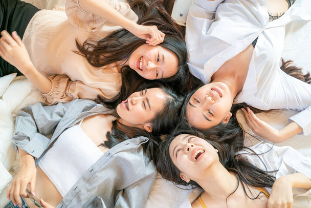Автопортрет привлекательных красивых девушек группы друзей, лежащих на белой кровати и говорящих винт глядя в камеру - Фото, изображение