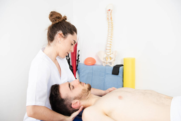 Физиотерапевт лечит мышцы шеи пациента без рубашки - Фото, изображение