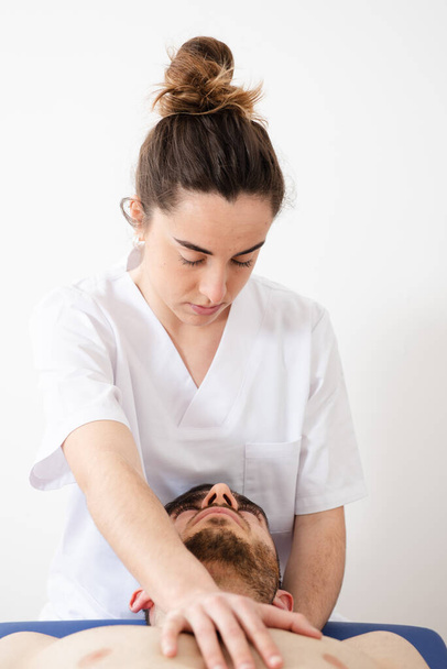 Fisioterapeuta tratando o pescoço de um paciente em fundo branco - Foto, Imagem