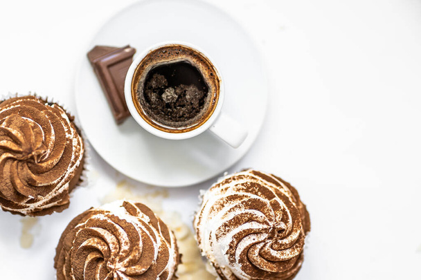 Fekete kávé sütikkel és muffinokkal. Fűszeres sütemények krémsajt cukormázzal, kakaóval díszítve - Fotó, kép