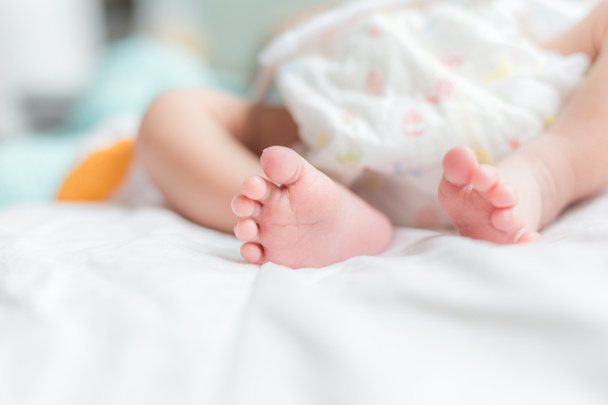 Χαριτωμένο μωράκι ξαπλωμένο στο κρεβάτι νεογέννητο μωρό πόδια σε λευκό κουβέρτα - Φωτογραφία, εικόνα