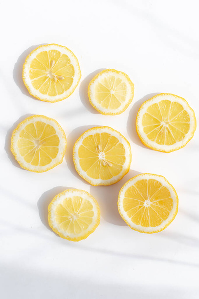 Limón en rodajas sobre fondo blanco. Diseño de limón. Fruta en rodajas. Color amarillo. Fondo blanco. Luz y sombra. Cítricos. Comida saludable. Copiar espacio - Foto, Imagen