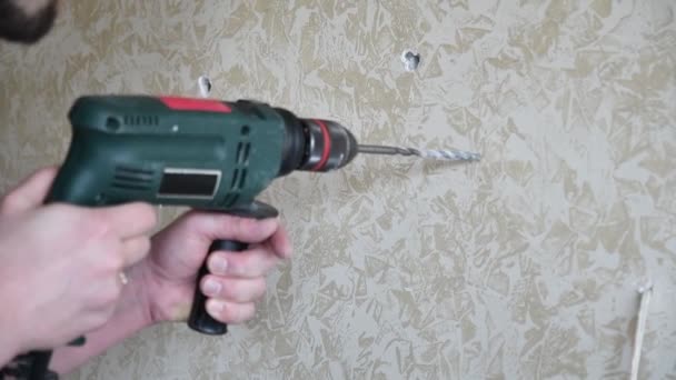Le mani dell'uomo lavorano con l'attrezzo di perforazione per fare il foro nella parete. Miglioramento domestico. Rallentatore - Filmati, video