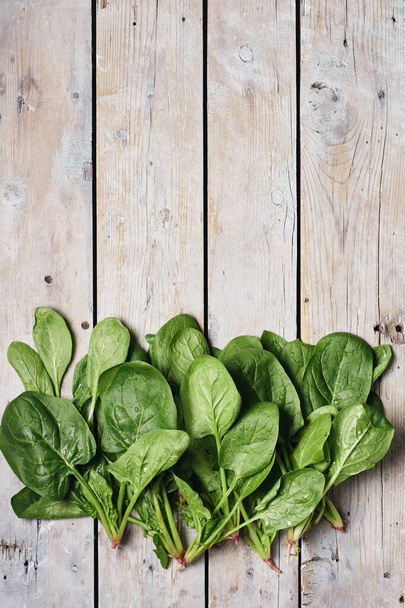 Green spinach leaves on a wooden surface, top view. - Foto, afbeelding