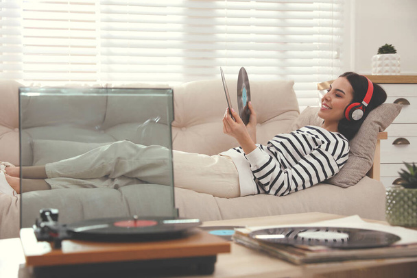 Woman listening to music with turntable in living room - Foto, Bild