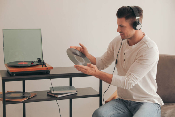 Happy man listening to music with turntable at home - Foto, imagen