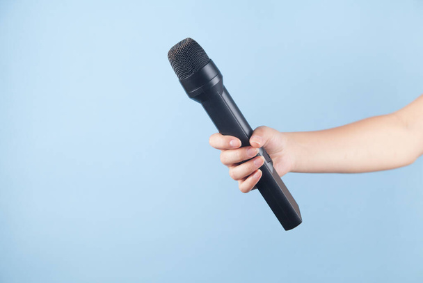 Mikrofon in der Hand eines Mädchens auf blauem Hintergrund. - Foto, Bild