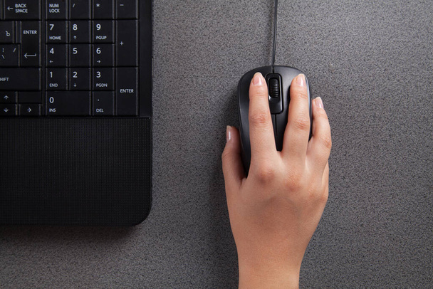 Woman's hand with computer mouse on table. Black computer.  - Foto, Bild