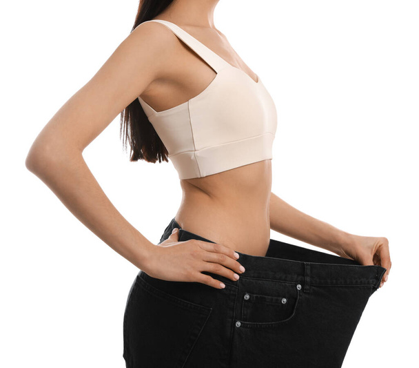 Young woman wearing big jeans after weight loss on white background, closeup - Valokuva, kuva