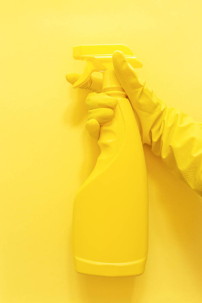 Yellow monochrome flat lay of cleaning tools. Hand in rubber gloves holding a spray bottle - Zdjęcie, obraz