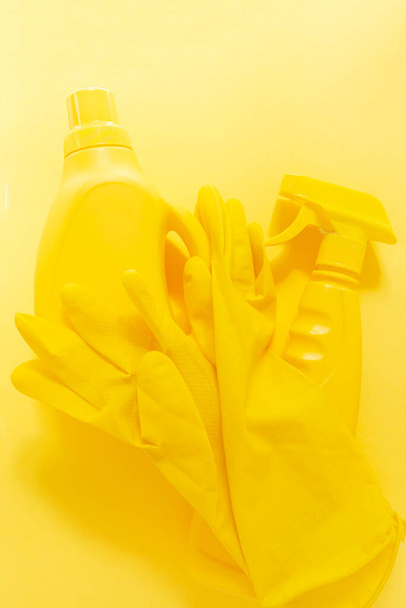 Yellow monochrome flat lay of cleaning tools. Colorful rubber gloves, spray, gel bottle - Foto, Imagem