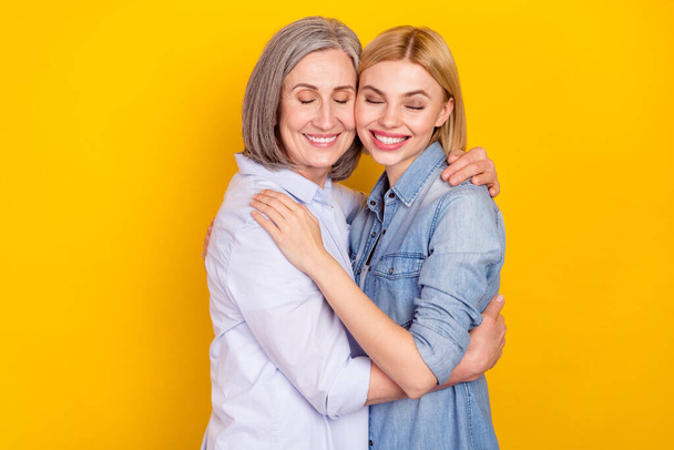 Photo portrait of dreamy happy granddaughter embracing her smiling granny isolated bright yellow color background - Photo, Image