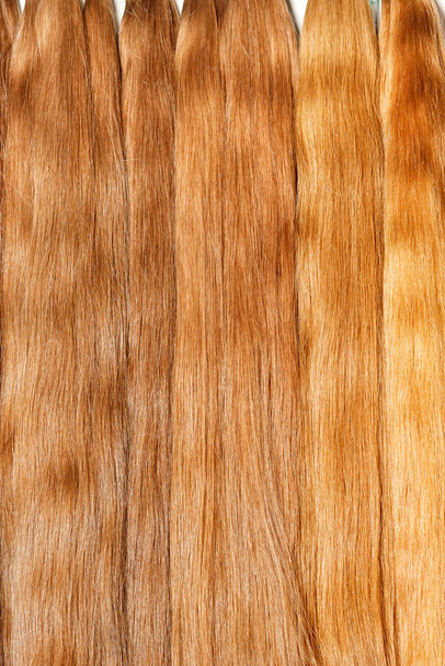 Natural shiny healthy human hair bundles in light wheat color for Hair extension wigs. Vertical image, close-up, copy space. - Photo, Image