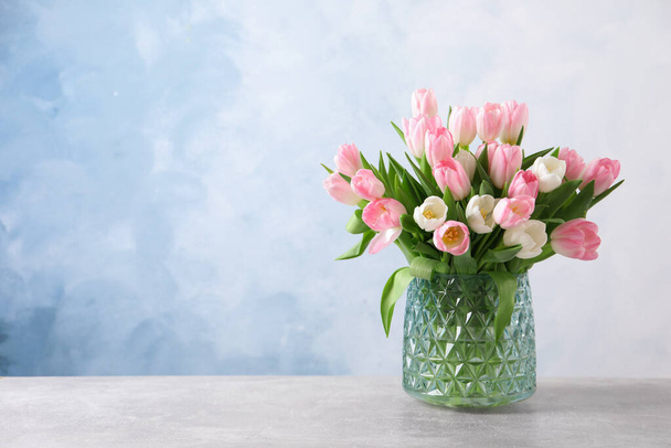 Beautiful bouquet of tulips in glass vase on light table. Space for text - Φωτογραφία, εικόνα